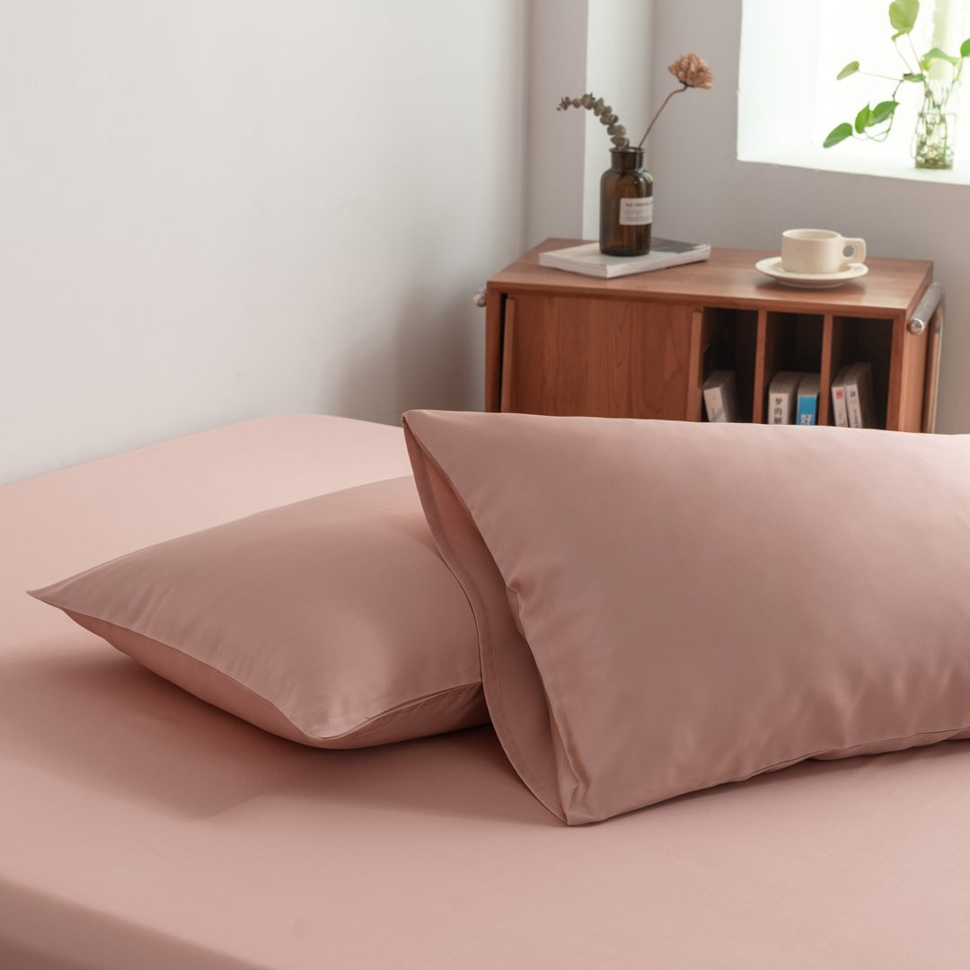 Foto van zijaanzicht van twee kussenslopen Cuddle Pink op een bed (kleur licht roze)