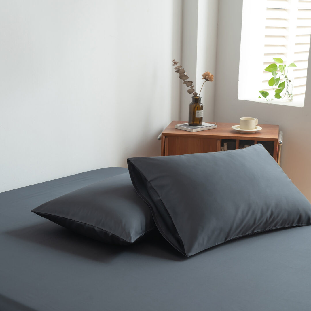 Foto van zijaanzicht van twee kussenslopen Space Blue op een bed (kleur donker blauw)