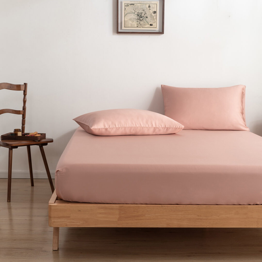 Twee kussenslopen Cuddle Pink op een bed als sfeerbeeld (kleur licht roze)