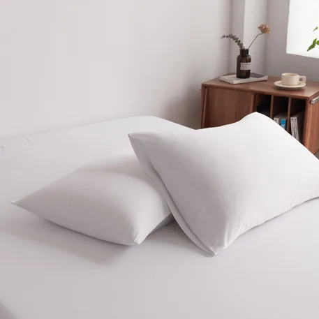 Foto van zijaanzicht van twee kussenslopen Coco White op een bed (kleur wit)
