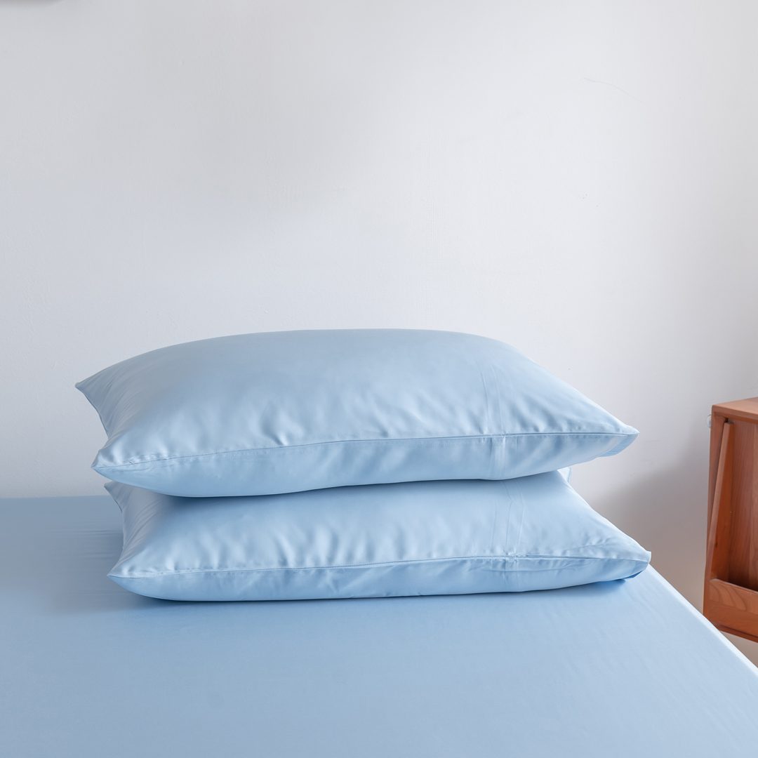 Foto van zijaanzicht van twee kussenslopen Sky Blue op een bed (kleur licht blauw)