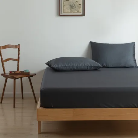 Close-up of a bamboo fitted sheet in Space Blue (dark blue) with matching pillowcases on a bed