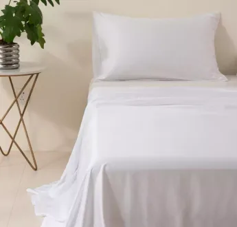 White bamboo flat sheet over a made bed with pillows, front view