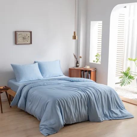 Bamboo duvet cover and pillowcases in Sky Blue (light blue) on a made bed in a bright bedroom, angled view