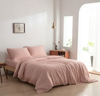 Bamboe dekbedovertrek en kussenslopen Cuddle Pink (roze) op een opgemaakt bed in een lichte slaapkamer, schuin aanzicht