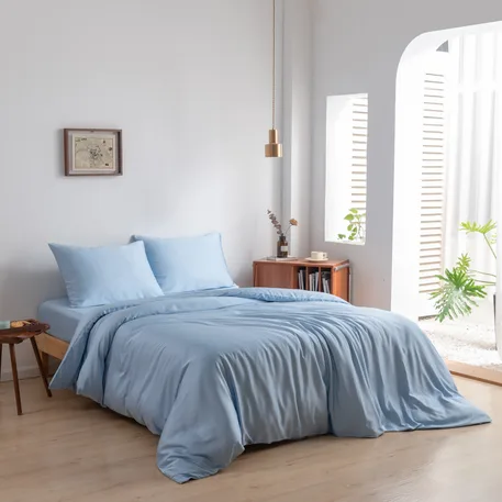 Bamboe dekbedovertrek en kussenslopen Sky Blue (lichtblauw) op een opgemaakt bed in een lichte slaapkamer, schuin aanzicht