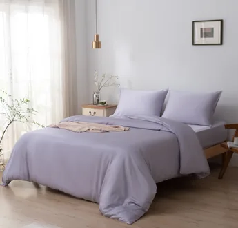 Bamboe dekbedovertrek en kussenslopen Lavender Mist (lila) op een opgemaakt bed in een lichte slaapkamer, schuin aanzicht