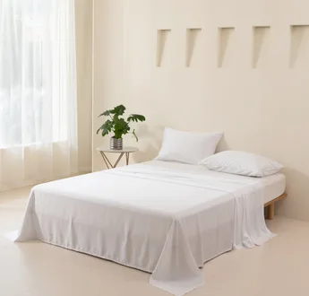 Wit bamboe laken op een opgemaakt bed in een lichte slaapkamer