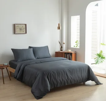 Bamboe dekbedovertrek en kussenslopen Space Blue (donkerblauw) op een opgemaakt bed in een lichte slaapkamer, schuin aanzicht