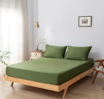 Bamboe hoeslaken Deep Moss (donkergroen) om een matras met twee bijpassende kussenslopen, schuin aanzicht