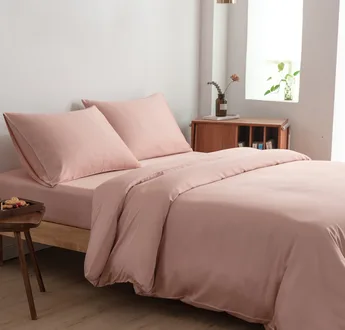 Bamboe beddengoedset Cuddle Pink (roze) op een opgemaakt tweepersoonsbed: dekbedovertrek, hoeslaken en kussenslopen