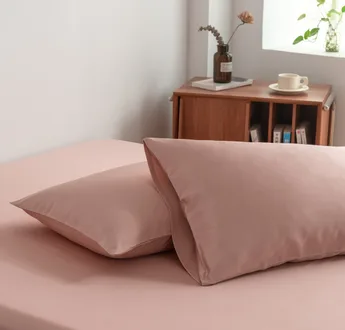 Foto van zijaanzicht van twee kussenslopen Cuddle Pink op een bed (kleur licht roze)