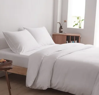 Bamboe beddengoedset Coco White (wit) op een opgemaakt tweepersoonsbed: dekbedovertrek, hoeslaken en kussenslopen