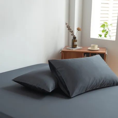 Foto van zijaanzicht van twee kussenslopen Space Blue op een bed (kleur donker blauw)