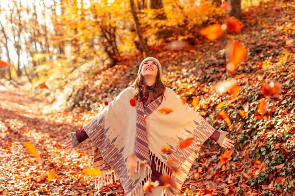 Iemand die geniet van de gevallen bladeren in de herfst