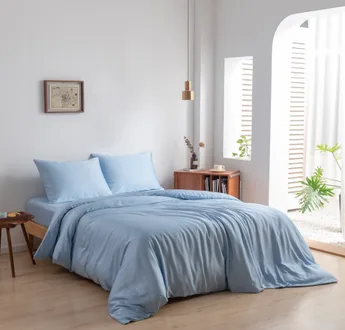 Bamboe dekbedovertrek en kussenslopen Sky Blue (lichtblauw) op een opgemaakt bed in een lichte slaapkamer, schuin aanzicht