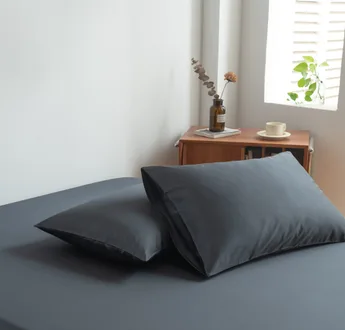 Foto van zijaanzicht van twee kussenslopen Space Blue op een bed (kleur donker blauw)