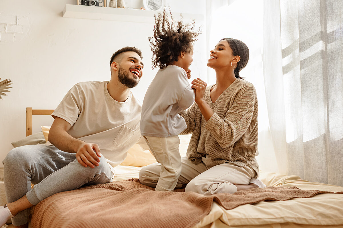 Een gezin met z'n alle op bed en een springend blij kind met bamboe beddengoed 