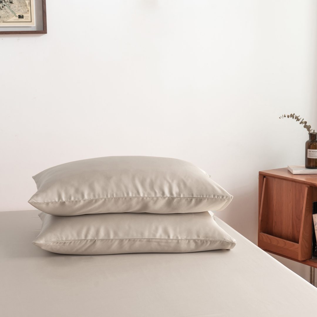 Foto van zijaanzicht van twee kussenslopen Soft Taupe op een bed (kleur licht bruin)