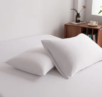 Foto van zijaanzicht van twee kussenslopen Coco White op een bed (kleur wit)