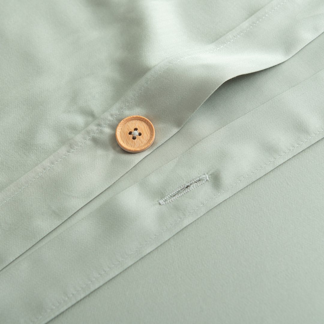Detailfoto van een bamboe knoopsluiting van een bamboe dekbedovertrek in de kleur Sage Green (licht groen)