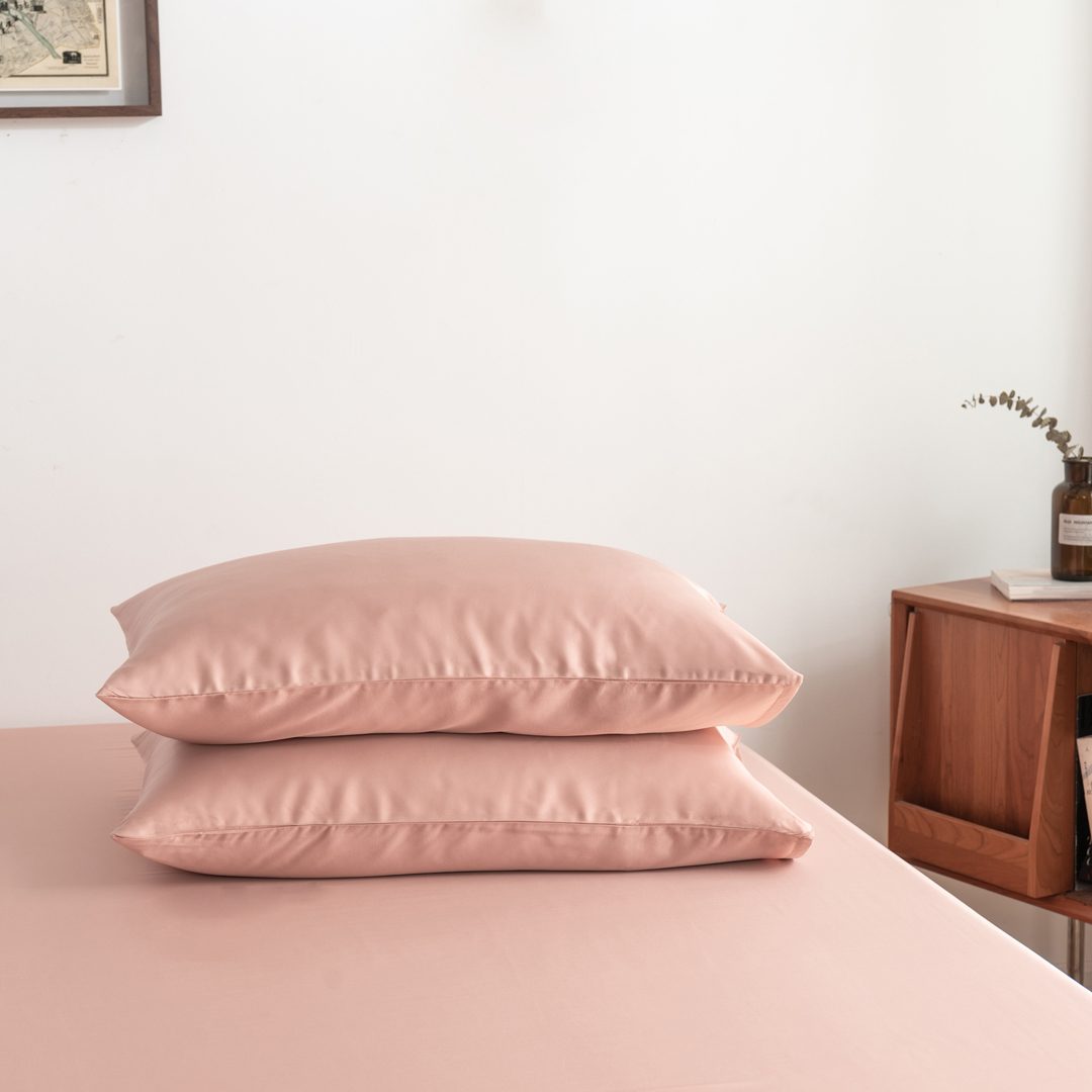 Foto van zijaanzicht van twee kussenslopen Cuddle Pink op een bed (kleur licht roze)
