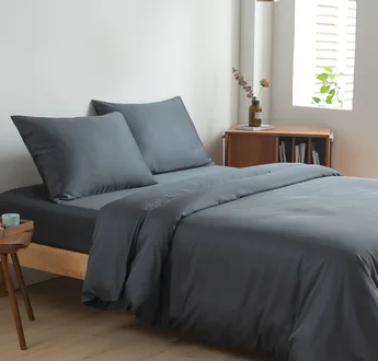 Bamboe beddengoedset Space Blue (donkerblauw) op een opgemaakt tweepersoonsbed: dekbedovertrek, hoeslaken en kussenslopen