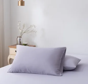 Twee bamboe kussenslopen Lavender Mist (lila) naast elkaar op een bed