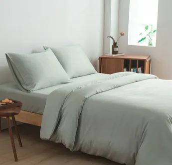 Bamboe beddengoedset Sage Green (saliegroen) op een opgemaakt tweepersoonsbed: dekbedovertrek, hoeslaken en kussenslopen