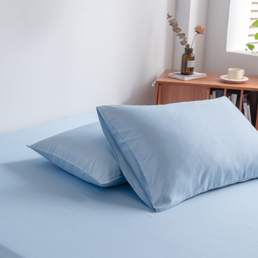 Foto van zijaanzicht van twee kussenslopen Sky Blue op een bed (kleur licht blauw)